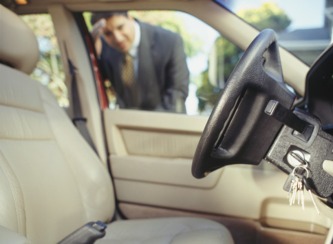 A person looking through a car window at keys locked inside, representing a lockout situation.