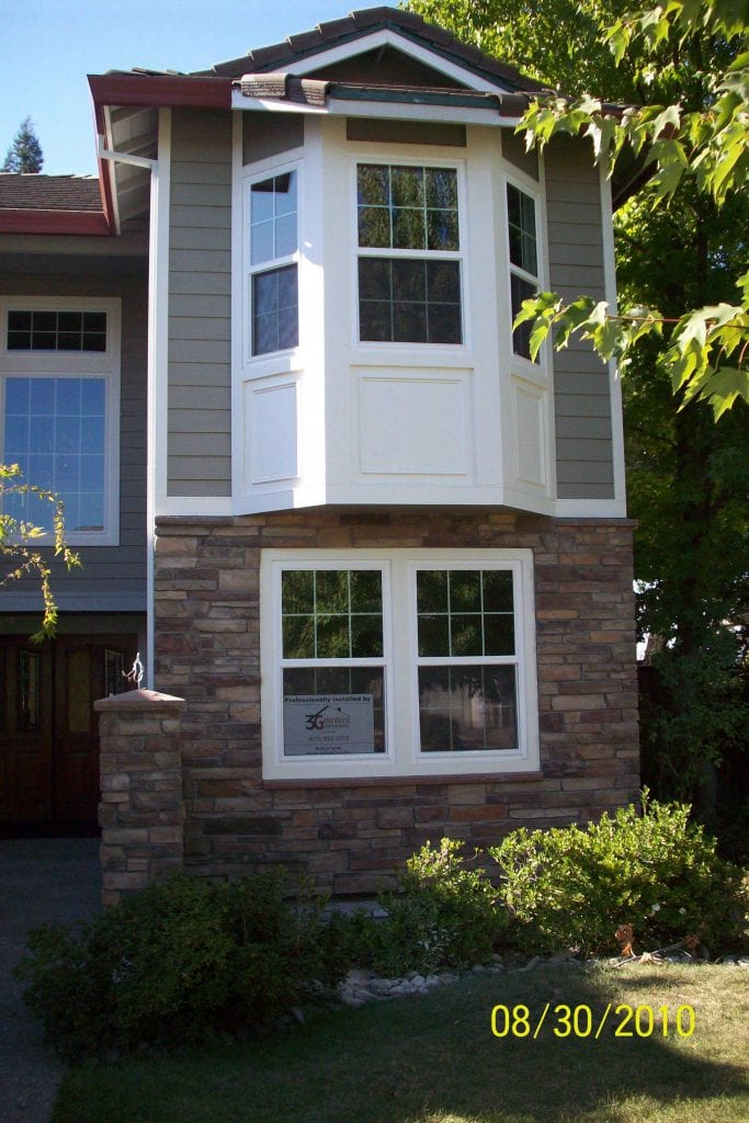 A house in Folsom featuring a bay window installed by 3 Generations Improvements, with a stone facade and green shrubbery in the foreground.