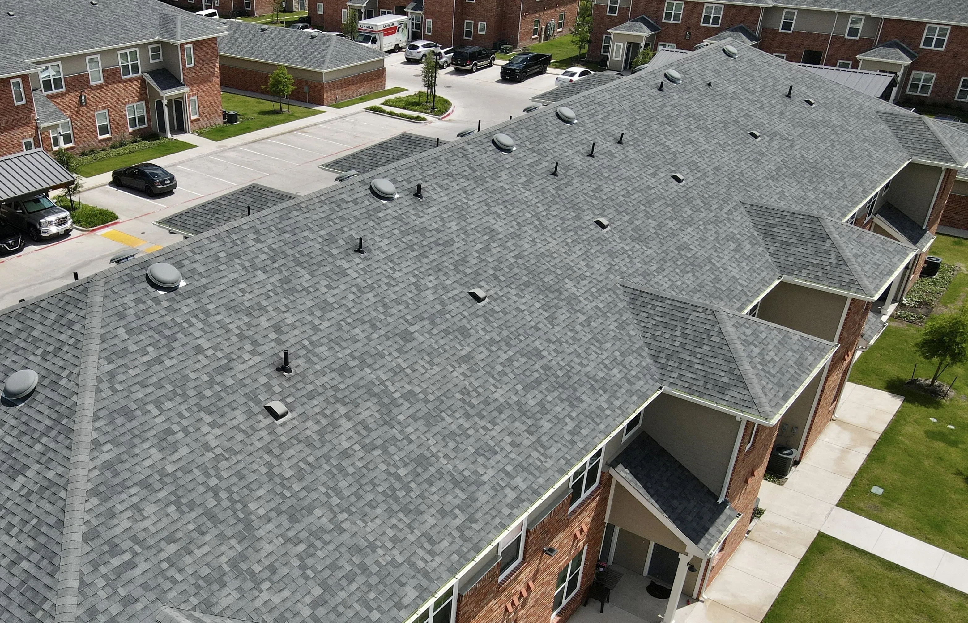 Aerial view of a large building complex with new gray shingle roofs installed by ARS General Contracting LLC in Wheat Ridge.