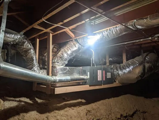 "Advanced ventilation system with insulated ducts and a central unit, showcasing efficient installation in a basement setting."