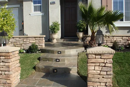 A well-designed front entrance with stone steps and pillars leading to a house, showcasing work by A Ramos Construction, Inc. in Brentwood.