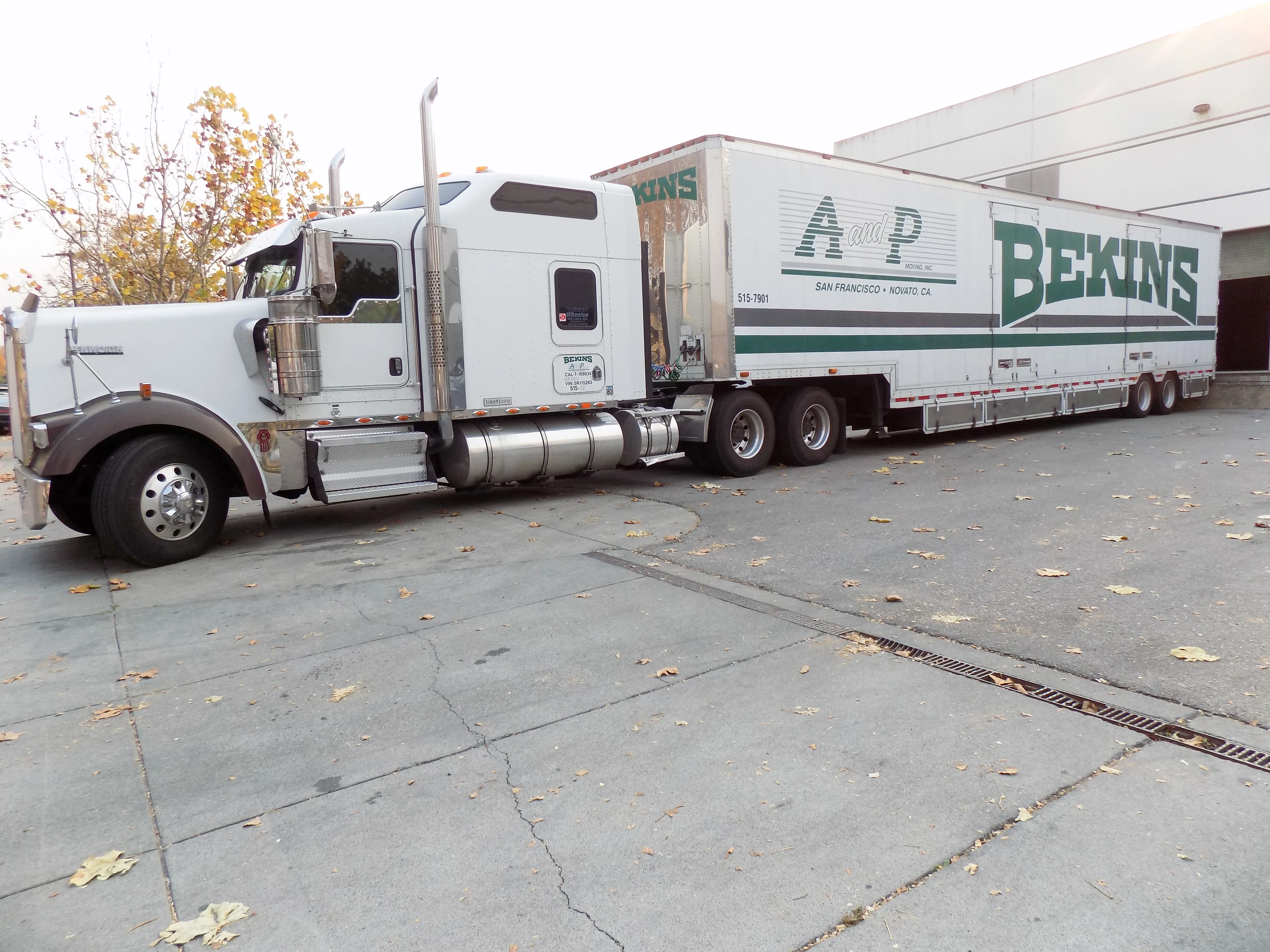 A white and green A and P Moving, Inc. truck parked outside a building, showcasing the company's branding in Novato.