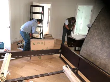 Two individuals assembling furniture in a room with moving boxes, showcasing the services of A and P Moving, Inc. in Novato.