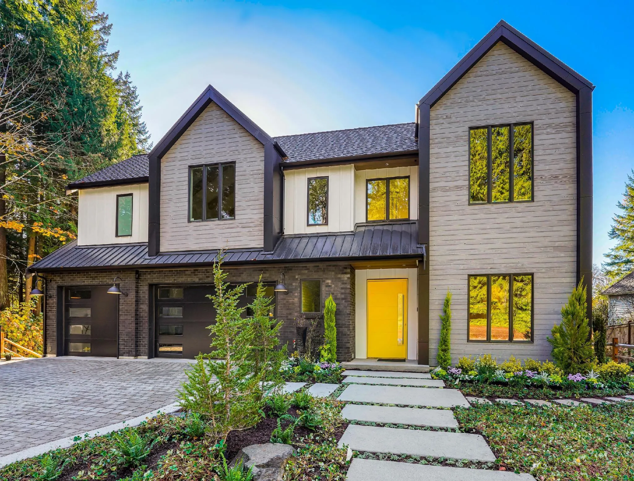 A modern two-story house with a vibrant yellow door, large windows, and a landscaped front yard, highlighting the work of Able Glass Company in Santa Clara.