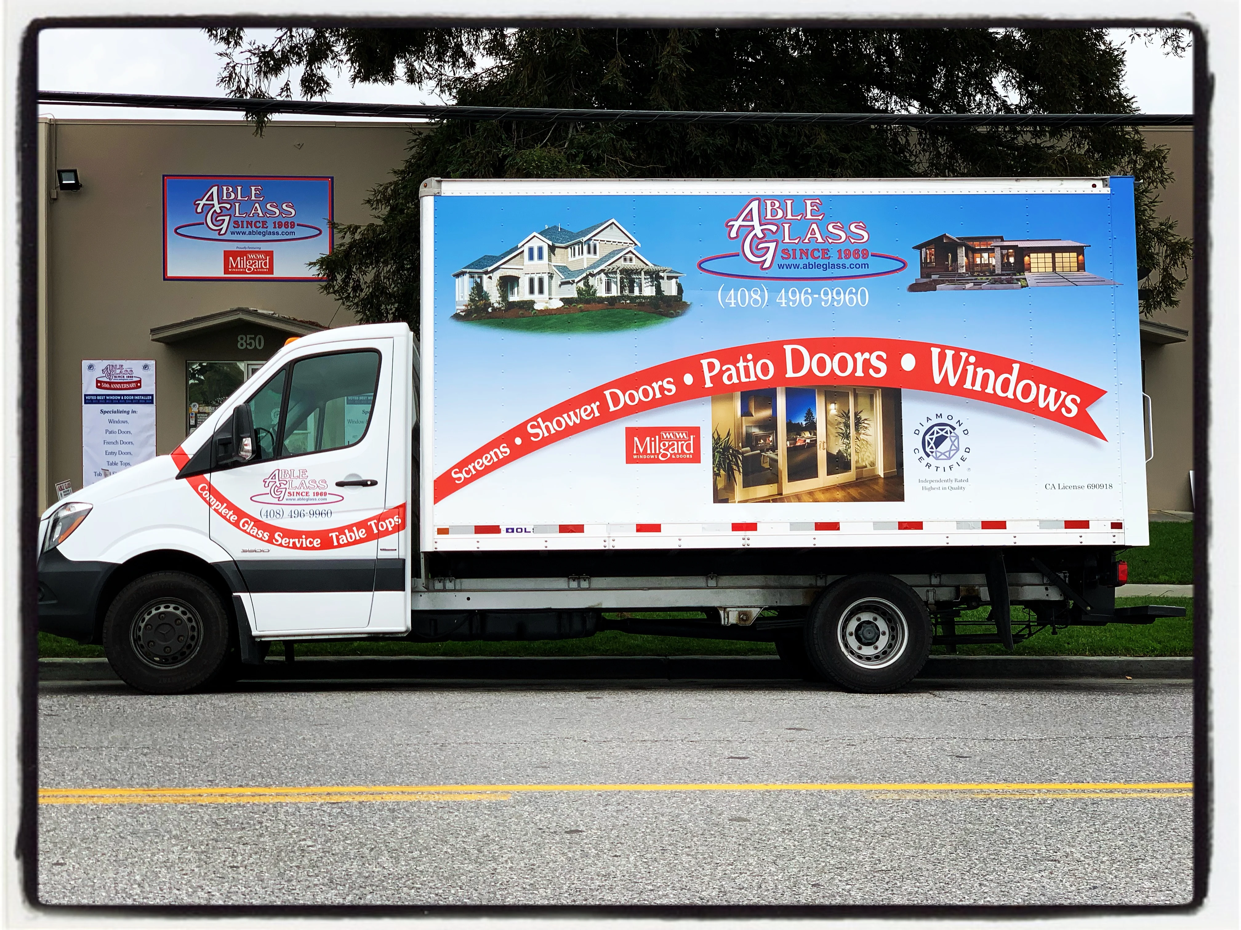 A delivery truck for Able Glass Company parked next to their building in Santa Clara, featuring promotional images of homes and glass services.