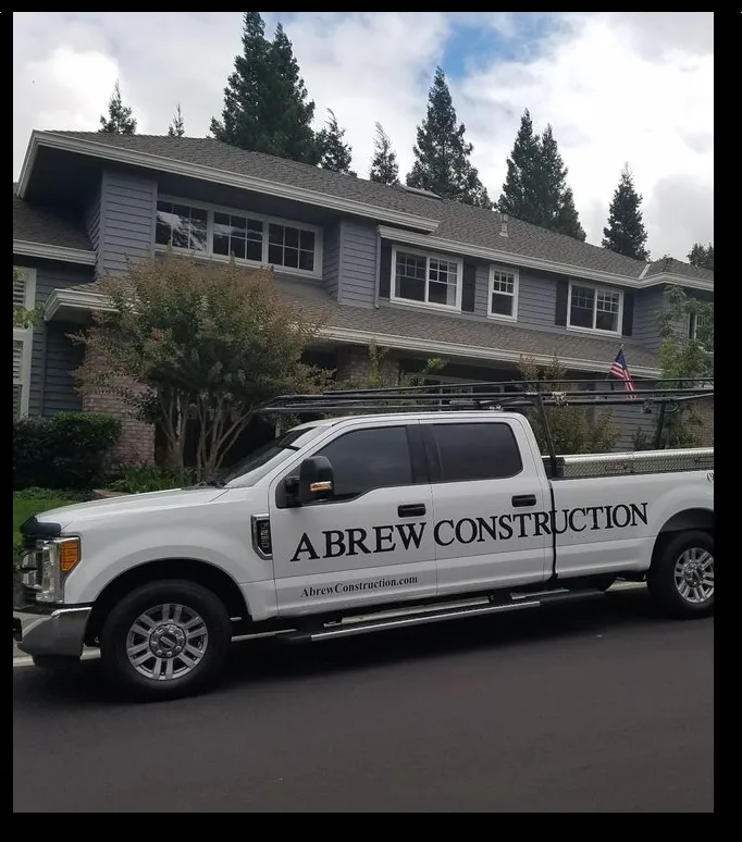 A white pickup truck labeled "Abrew Construction" is parked in front of a large two-story house with trees and an American flag in Pleasanton.