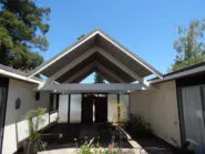 A modern residential building with a large, gabled roof under a clear blue sky, showcasing the architectural design expertise of Abril Roofing, Inc. in Martinez.