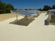 Solar panels installed on a flat roof by Abril Roofing, Inc. under a clear blue sky in Martinez.