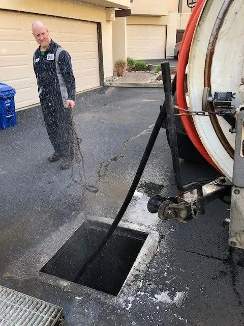 "A technician from AbsolutePlumbingandDrain in Concord operating equipment to clear an outdoor drain."