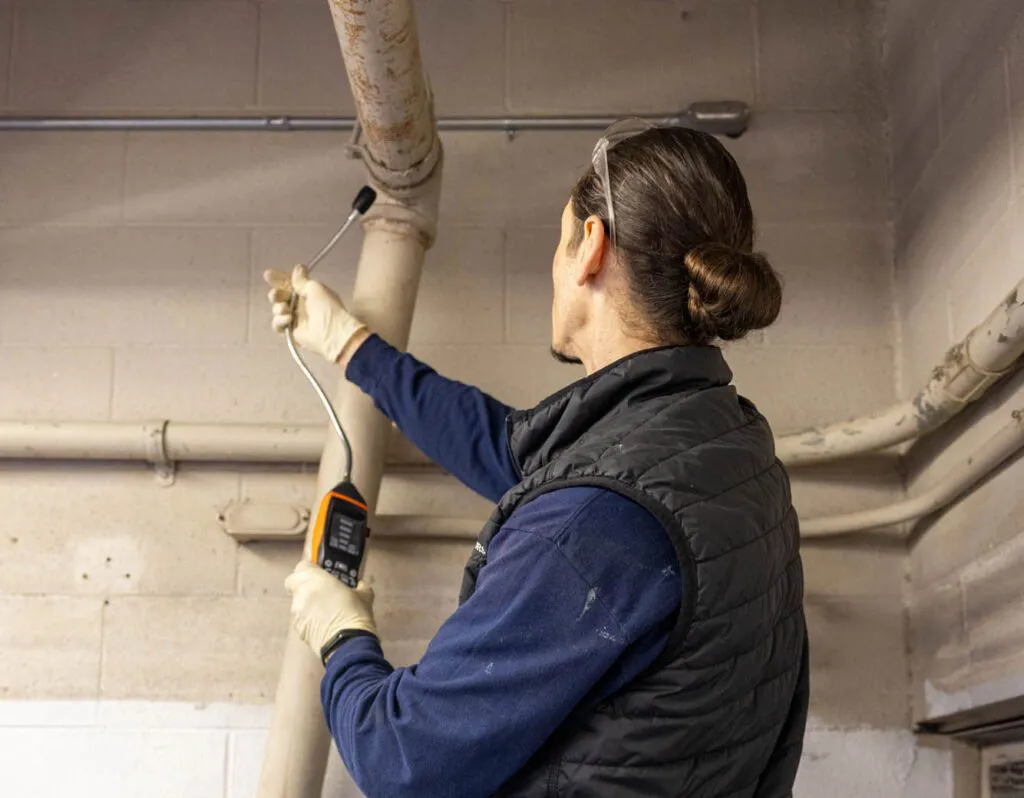 A technician from Ace Plumbing and Rooter inspecting a pipe using professional equipment in a San Francisco basement.