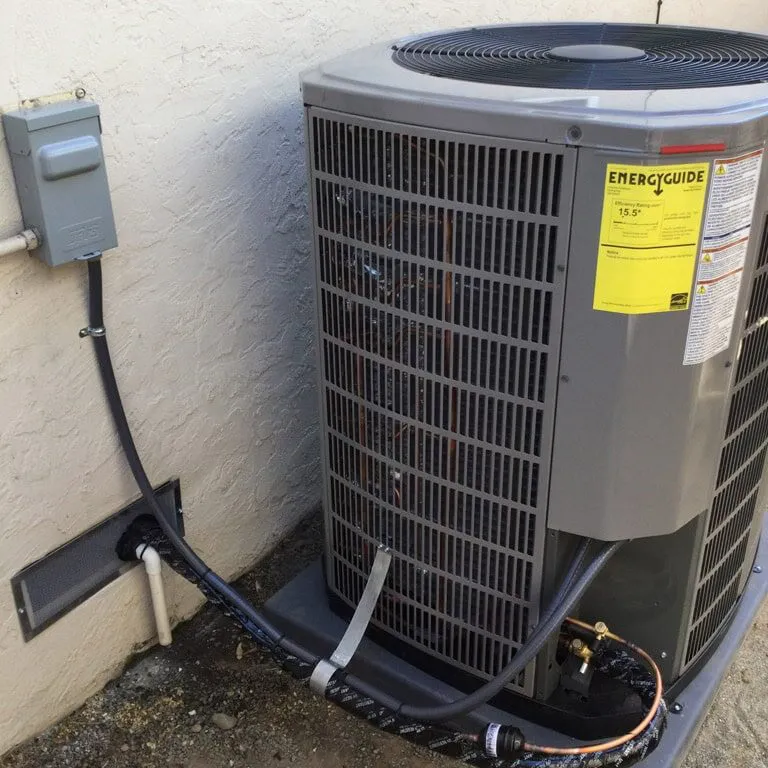 An outdoor air conditioning unit installed against a textured wall, showcasing an EnergyGuide label.