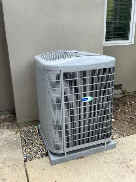 A gray outdoor HVAC unit installed next to a house, representing the efficient systems used by Air Quality Heating & Air Conditioning in San Jose.