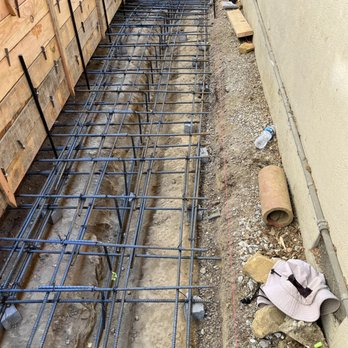 Construction site showing steel rebar laid out in preparation for concrete pouring, next to a building foundation in Castro Valley.