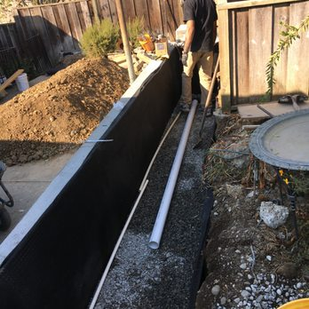 A worker from Alameda Engineering involved in a construction project, installing piping and working with earth materials in Castro Valley.