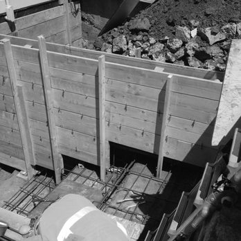 Black and white image of a construction site showing wooden forms and metal reinforcement bars at Alameda Engineering in Castro Valley.