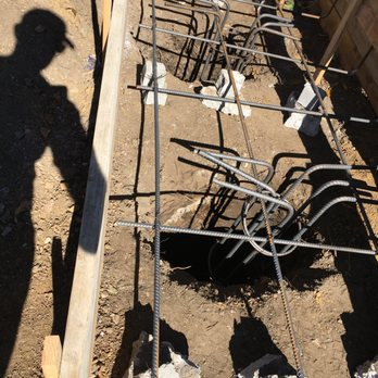 Construction site with rebar and foundation work, shadow of a person visible.