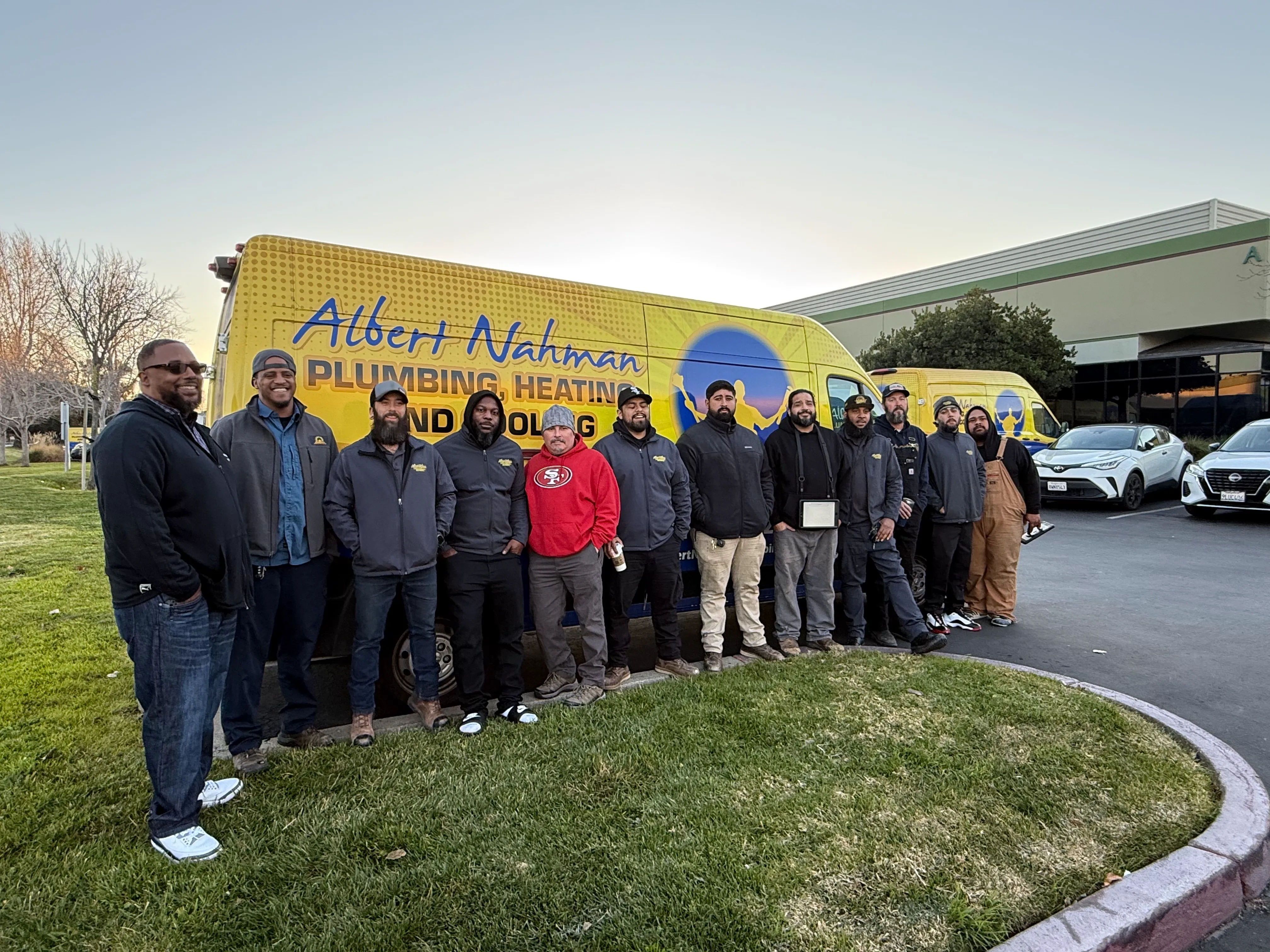 A group of employees from Albert Nahman Plumbing, Heating and Cooling stand in front of their company van in Alameda.
