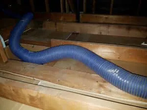 A blue hose installed in an attic, placed among wooden beams at AllBayInsulation&HVAC in SanJose, highlighting efficient HVAC solutions.