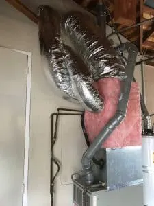 A poorly installed HVAC duct system with silver insulation and pink insulation panels.
