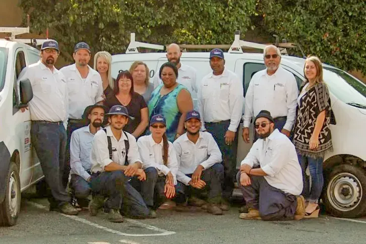 A group photo of the All N One Pest Eliminators team in Antioch, standing and kneeling in front of a company van.