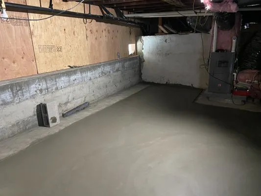 Image of a freshly poured concrete basement floor with unfinished walls, demonstrating construction work by All Seasons Construction in Oakland.