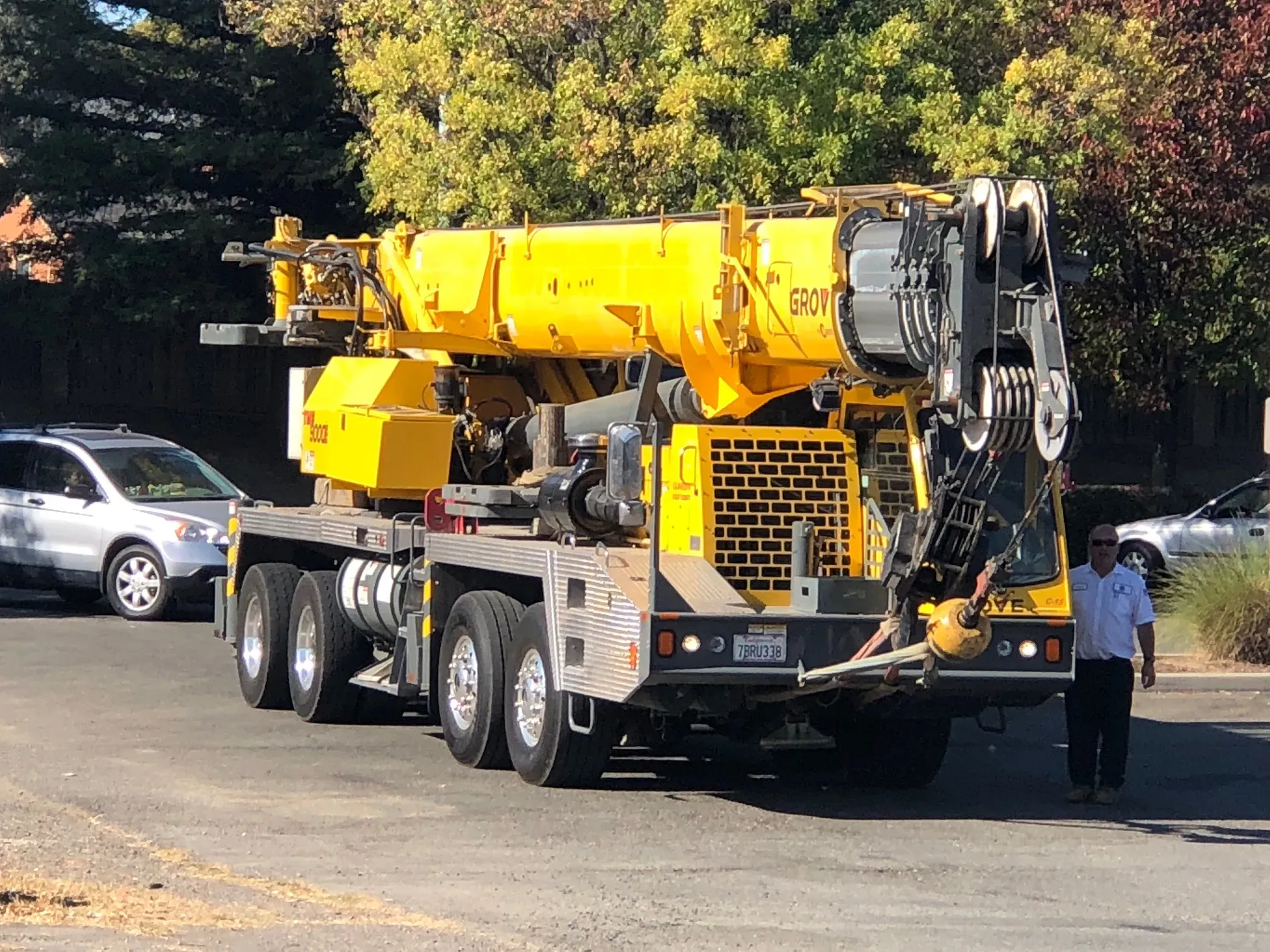 "A yellow crane truck from All Weather Heating & Air Conditioning Inc. in Vacaville, parked on a street with a technician standing beside it."
