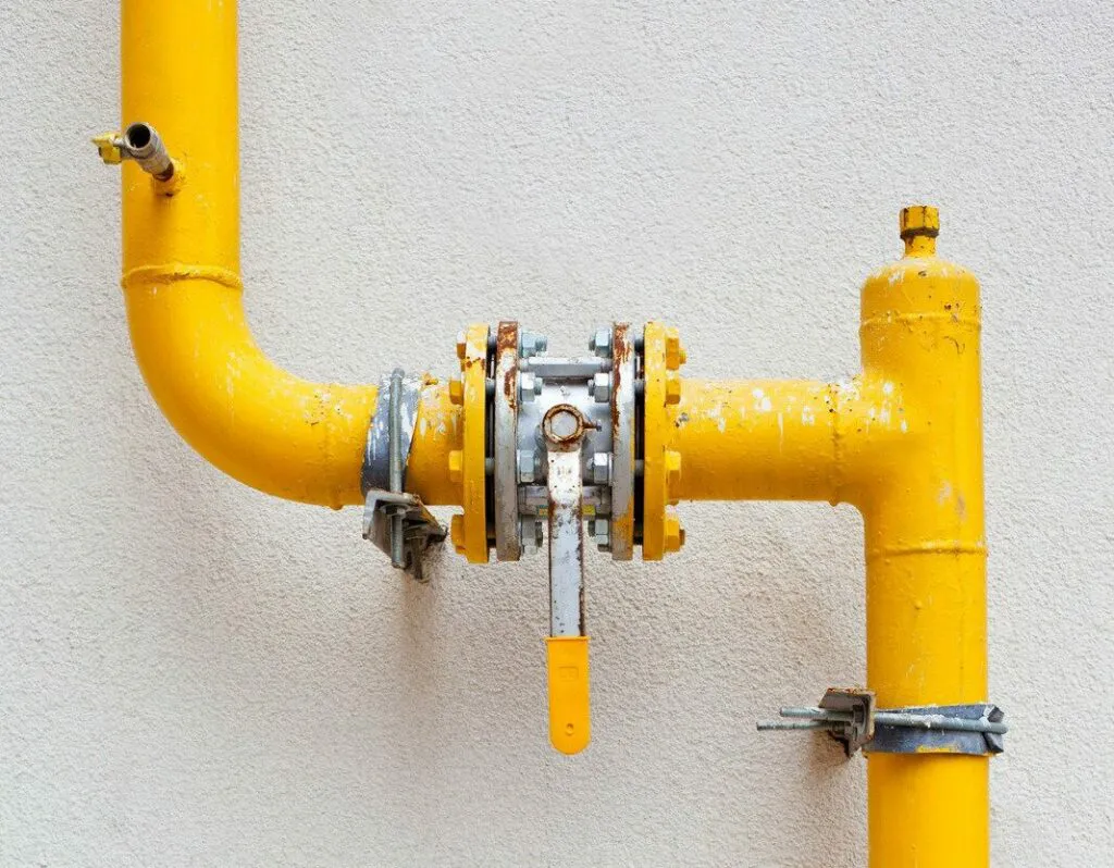 "Close-up of a yellow industrial valve and pipe system on a wall, representing plumbing services by Allstar Plumbing in San Jose."