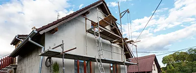 A house under renovation with scaffolding against the facade, showcasing Alltek Restoration, Inc.'s meticulous work in Pittsburg.