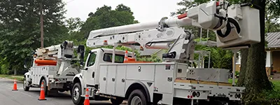 Utility trucks from Alltek Restoration, Inc. lined up on a tree-lined street in Pittsburg, equipped for maintenance work.