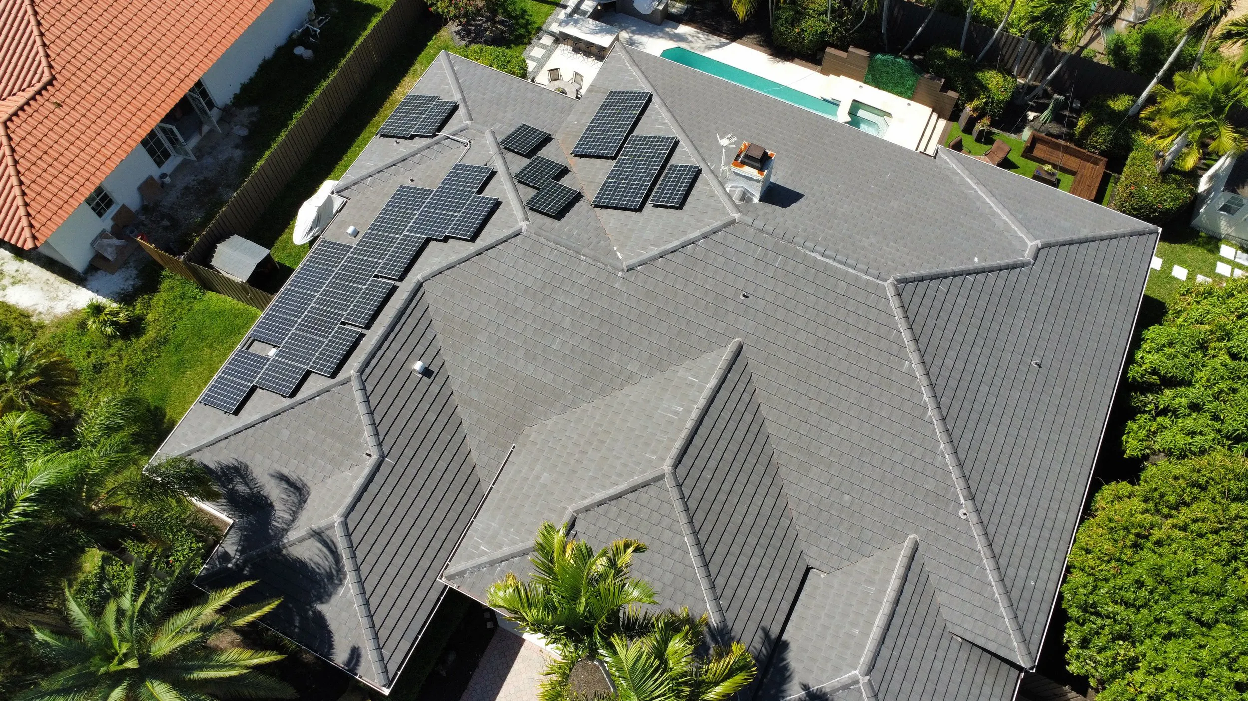 "Aerial view of a residential roof with solar panels installed, showcasing Alonso Roofing's work in Hialeah."