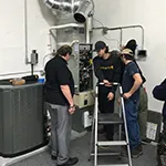 A group of technicians from Alternative Heating & Air Conditioning Solutions, Inc. working together on an HVAC installation in San Carlos, with various equipment visible.