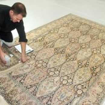 A person carefully attending to a detailed rug, showcasing the skilled craftsmanship at Artisan Rug Care in Santa Cruz.