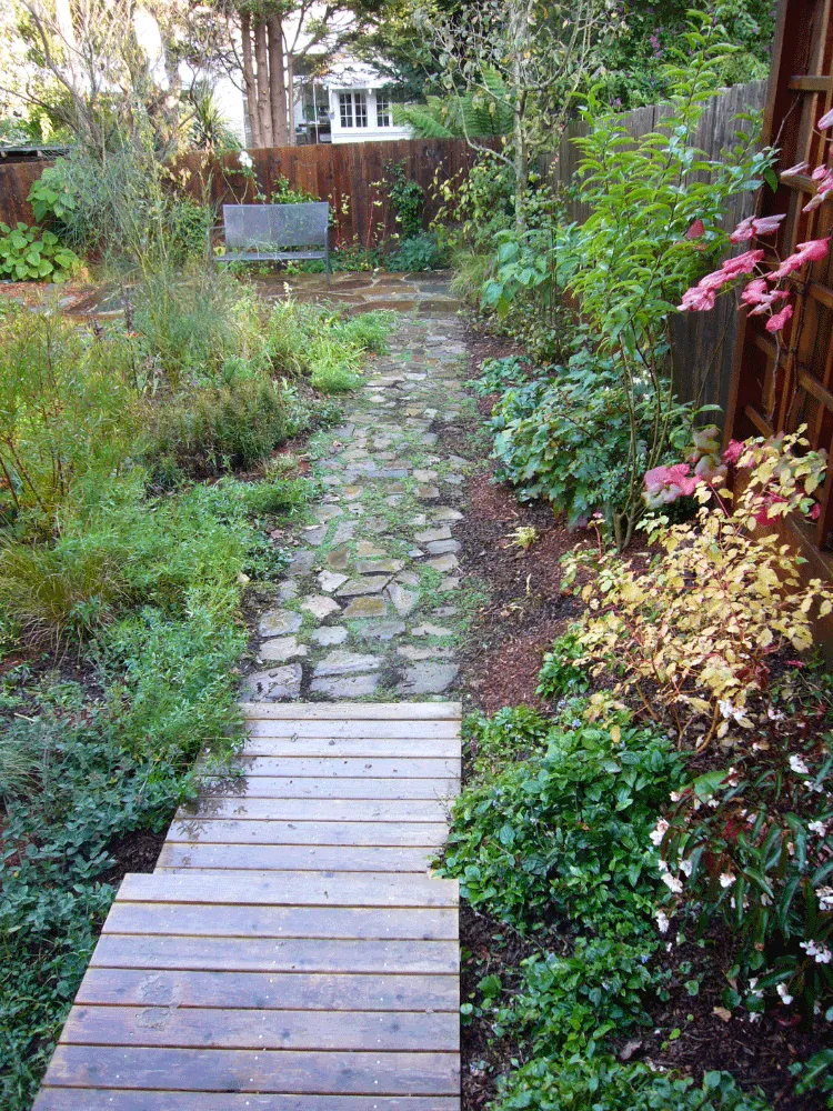 A garden in San Francisco featuring a stone path surrounded by lush greenery, designed by Artisans Landscape Inc.