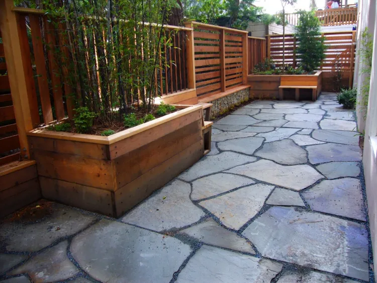 A beautifully designed outdoor space featuring a stone patio and wooden planters with greenery, created by Artisans Landscape Inc in San Francisco.