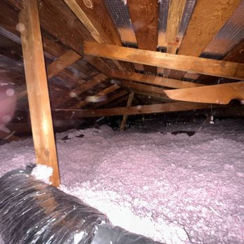 Attic filled with pink insulation material and wooden beams, demonstrating the work of AtticElite Insulation Solutions in San Jose.