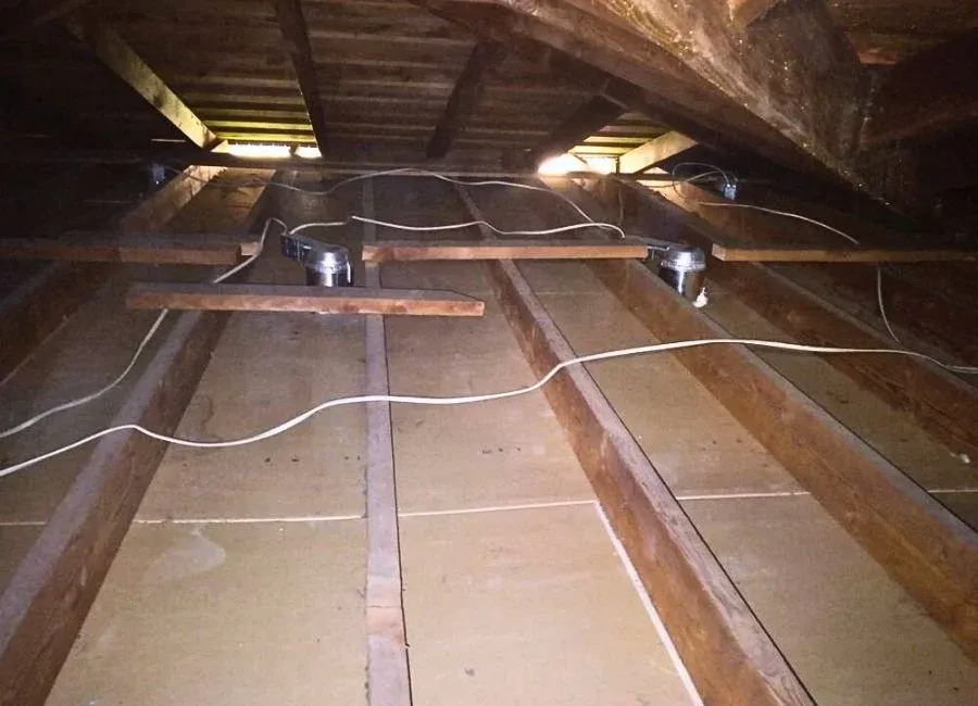 A clutter-free attic in SanJose with neatly arranged wooden beams and electrical installations, demonstrating the meticulous work of AtticBros.