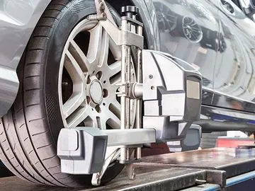 A close-up image of a car wheel being aligned using specialized equipment in an auto repair shop.