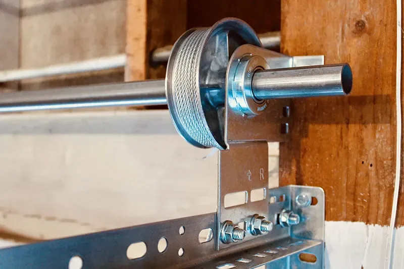 Close-up of a garage door mechanism showing a metal cable and pulley system, highlighting the engineering quality of Automatic Garage Door Corporation in San Francisco.
