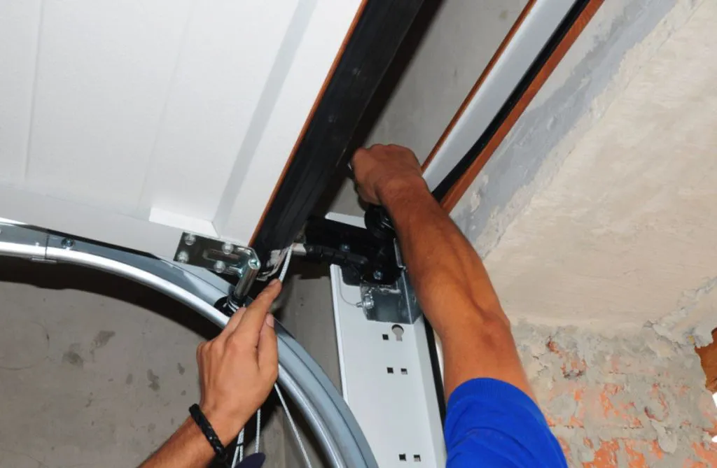 "A person installing a garage door, focusing on the mechanical components and track, by Automatic Garage Door Corporation in San Francisco."