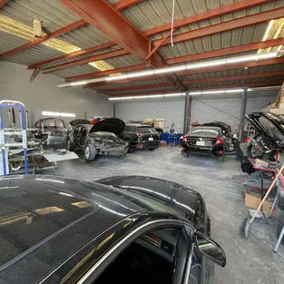 Interior of an auto repair shop with multiple vehicles being serviced at the Automobile Collision Center in Hayward.