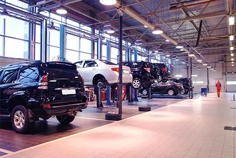 Inside view of the Automobile Collision Center in Hayward with multiple vehicles on lifts undergoing repair in a spacious workshop.