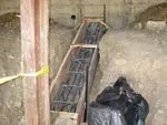 A construction site showing a concrete framework reinforced with steel bars, partially surrounded by dirt, by BB & B Builders Inc. in Mendocino.