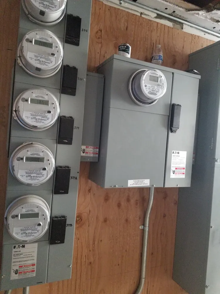 A series of electrical meters and a junction box installed on a wooden wall by BV Electric Inc. in San Francisco.