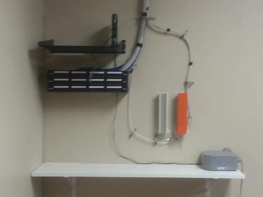 A wall-mounted network setup with cables and electronic devices organized neatly in an office space, installed by B. Henry's Quality Electric Inc. in Petaluma.