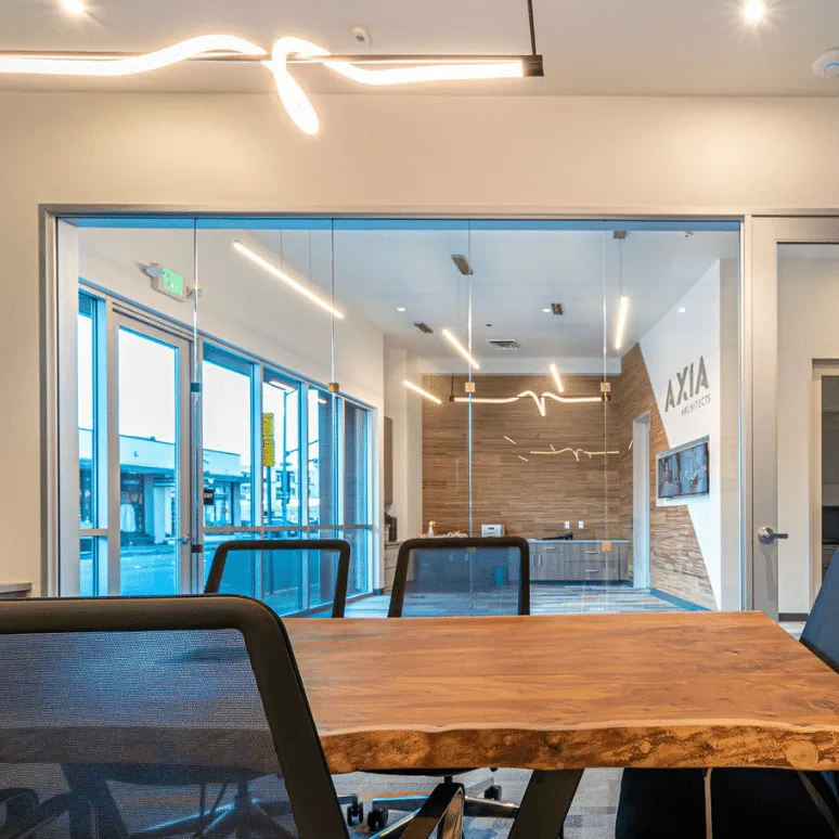 A contemporary conference room featuring a glass wall by B & L Glass in Santa Rosa, with sleek lighting and a wooden table.