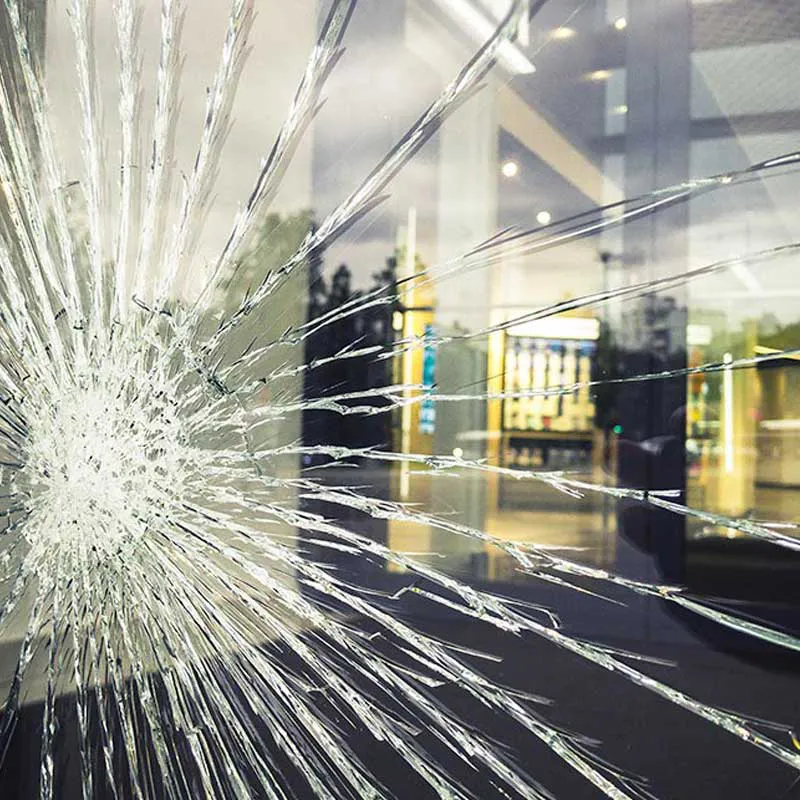 Close-up of a cracked glass window reflecting a cityscape, illustrating the need for glass repair services by B & L Glass in Santa Rosa.