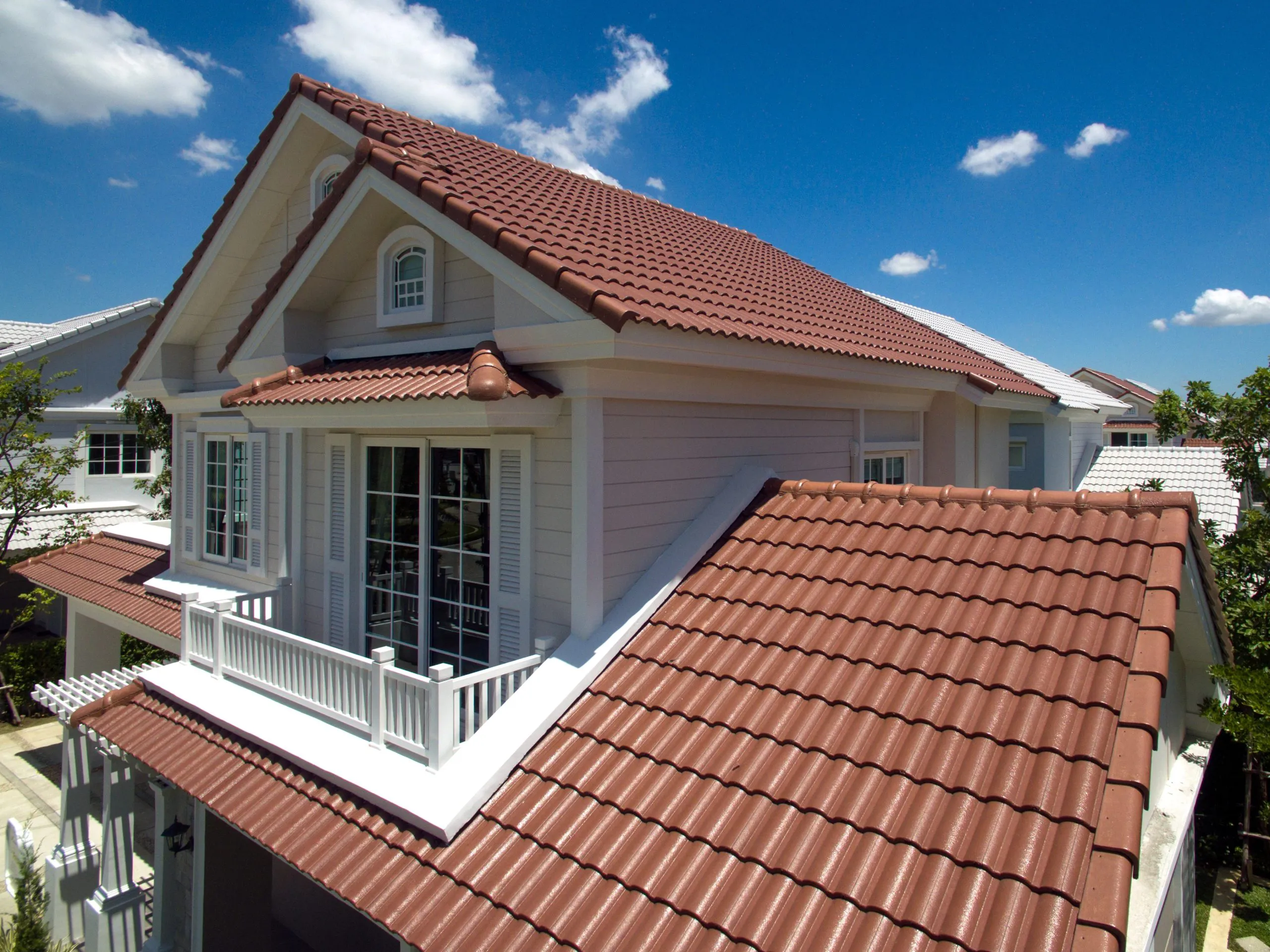 "A house in Alviso featuring a newly installed tiled roof by Bay 101 Roofing, Inc., displaying red tiles and white trim against a blue sky."