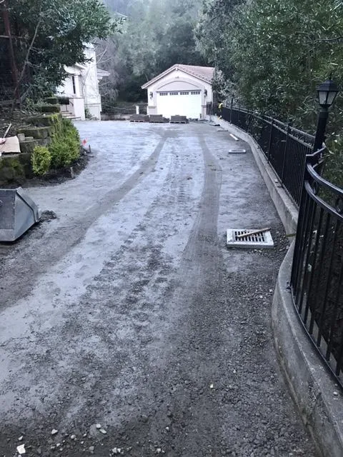 Image of a gravel driveway with a drainage system in Moraga, installed by Bay Area Drainage, Inc., featuring a visible trench drain running alongside a black metal fence.