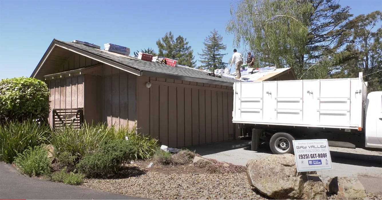 Workers from Bay Valley Roofing repairing a roof on a house in Concord, with equipment and materials on site.