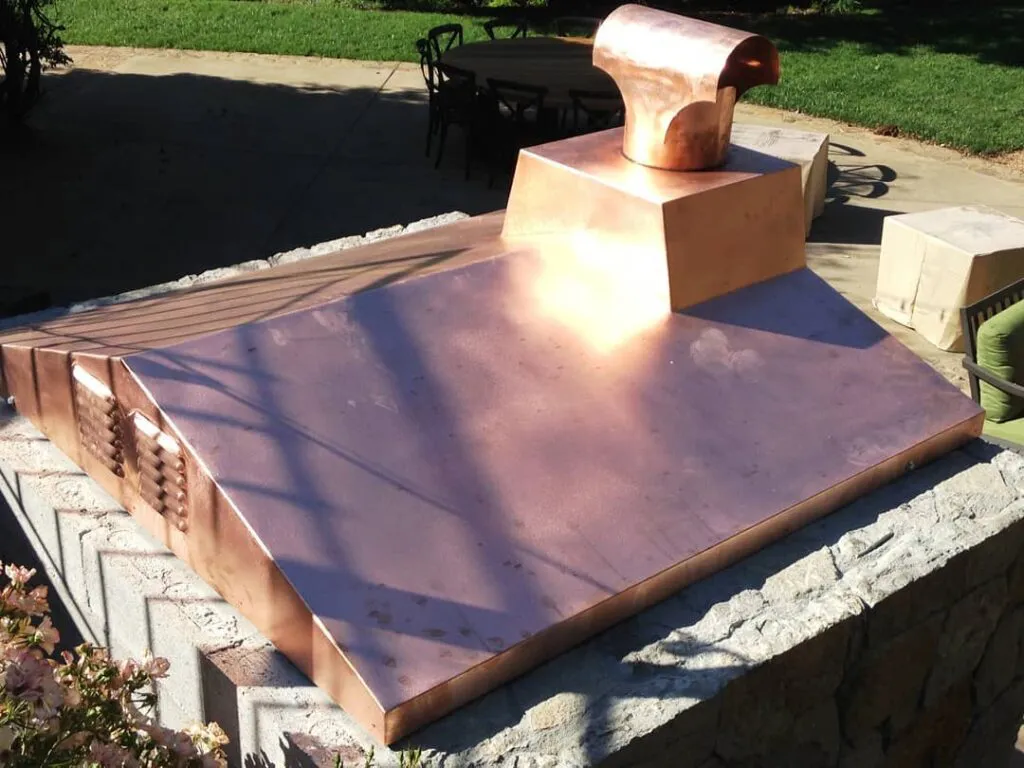 Copper ventilation structure installed outdoors on a stone base, with a focus on its shiny surface and robust build by Bell Products, Inc. in Napa.
